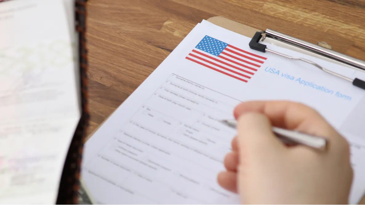 closeup of people filling visa application forms with personal passports