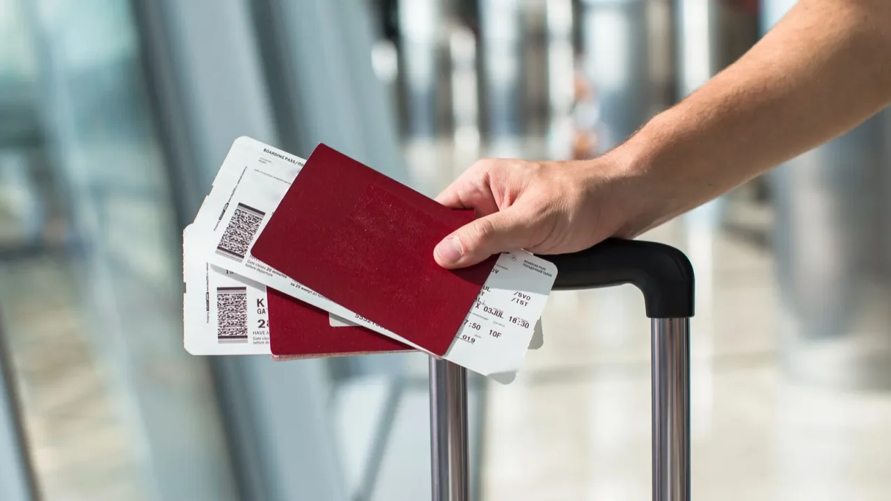 closeup of man holding passports and boarding pass at airport