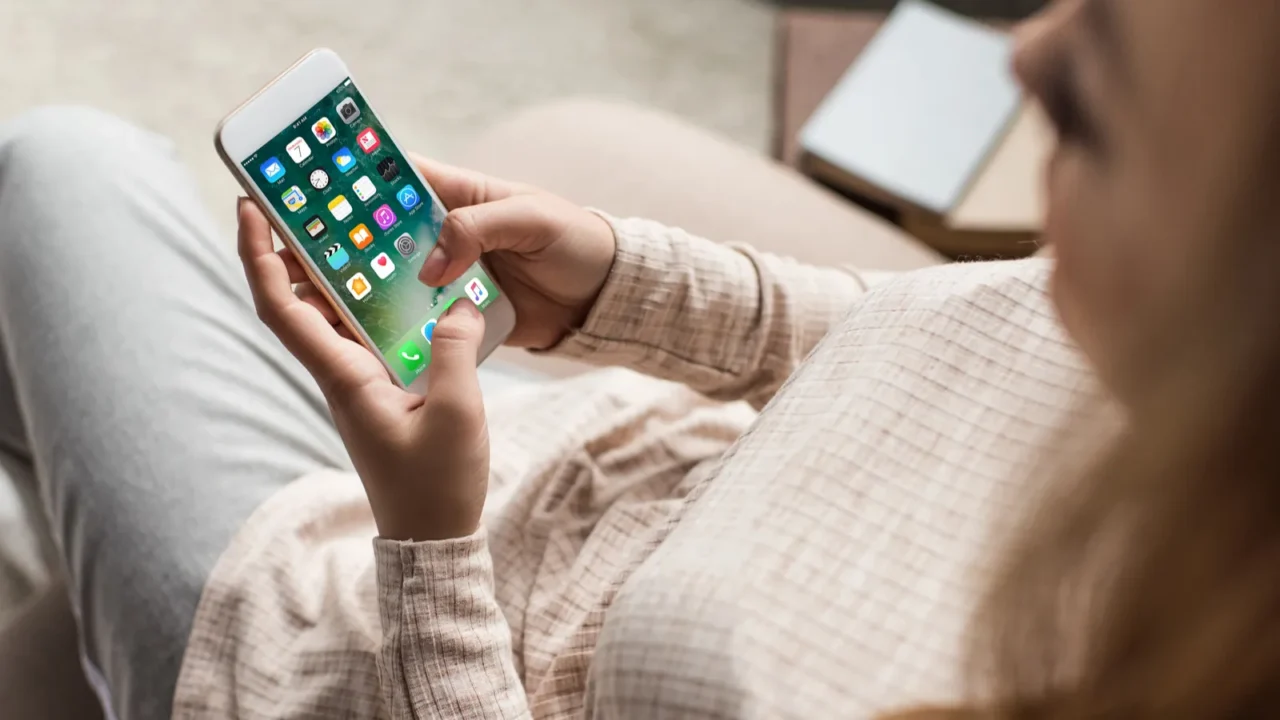 cropped shot of woman on couch using smartphone with ios