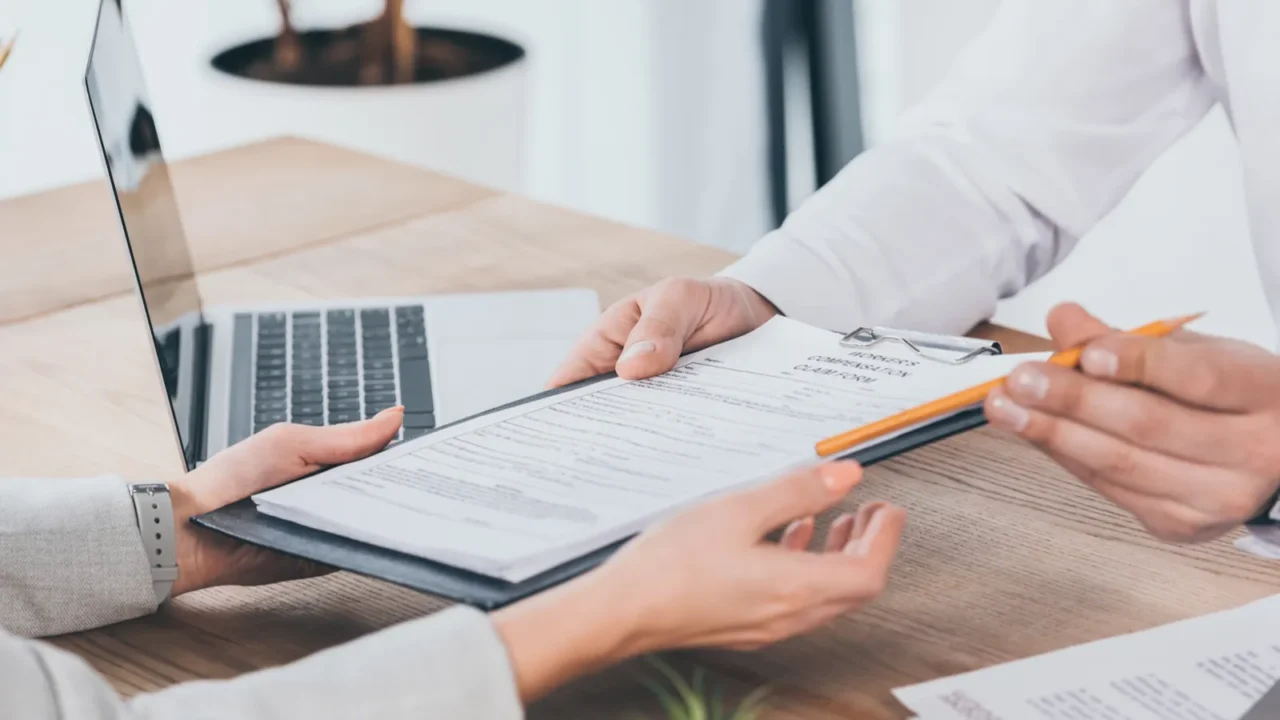 cropped view of businessman giving compensation claim form to woman