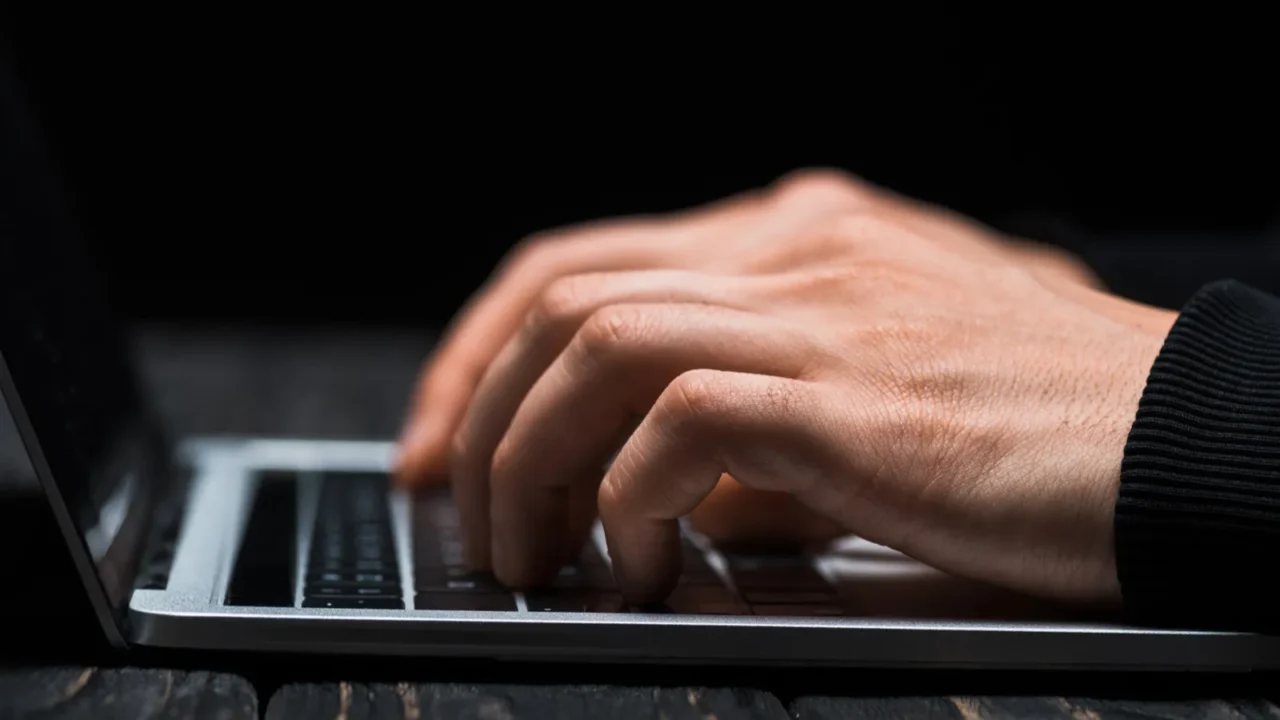 cropped view of hacker typing on laptop keyboard isolated on