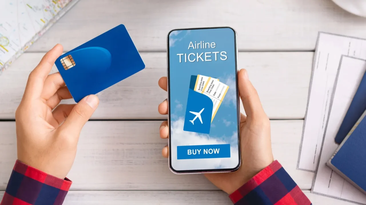 man holding credit card and smartphone buying plane tickets online