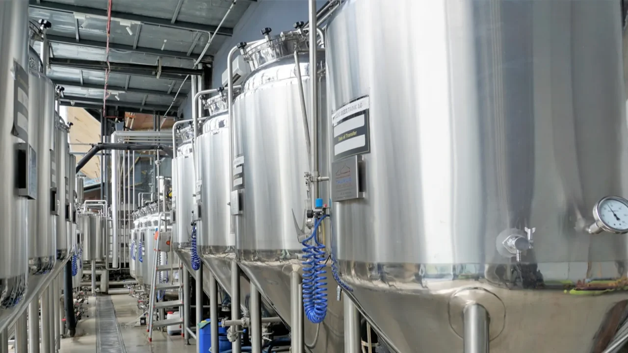row of shiny metal micro brewery tanks or fermentation mash