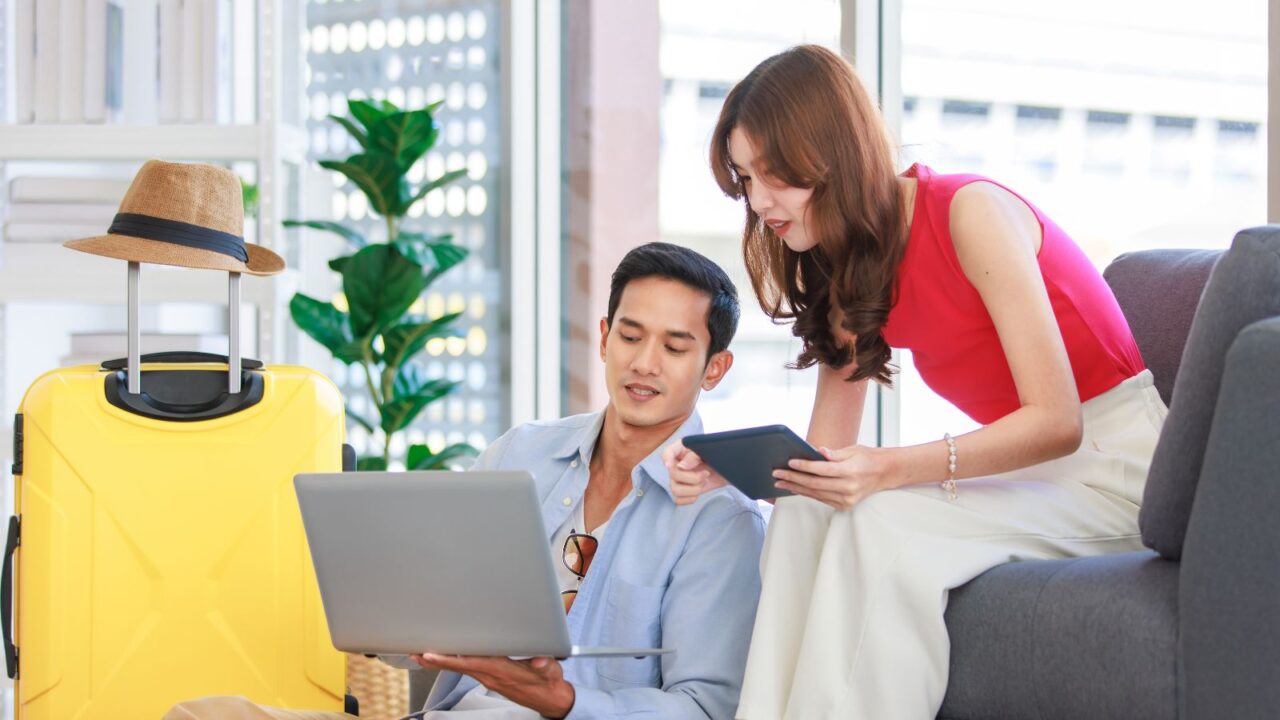 Asian young lovely boyfriend and girlfriend traveler couple sitting and booking flights.