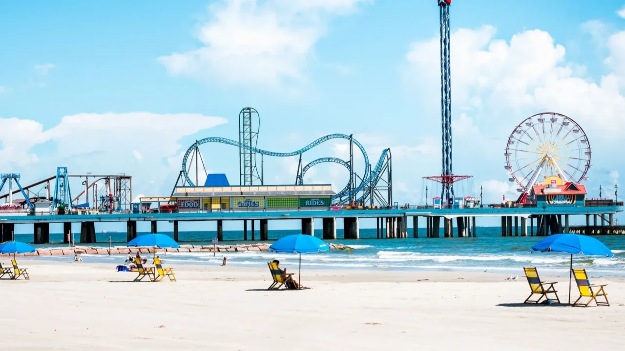 A landscape of the Galveston Island Historic Pleasure Pier under a blue cloudy sky and sunlight