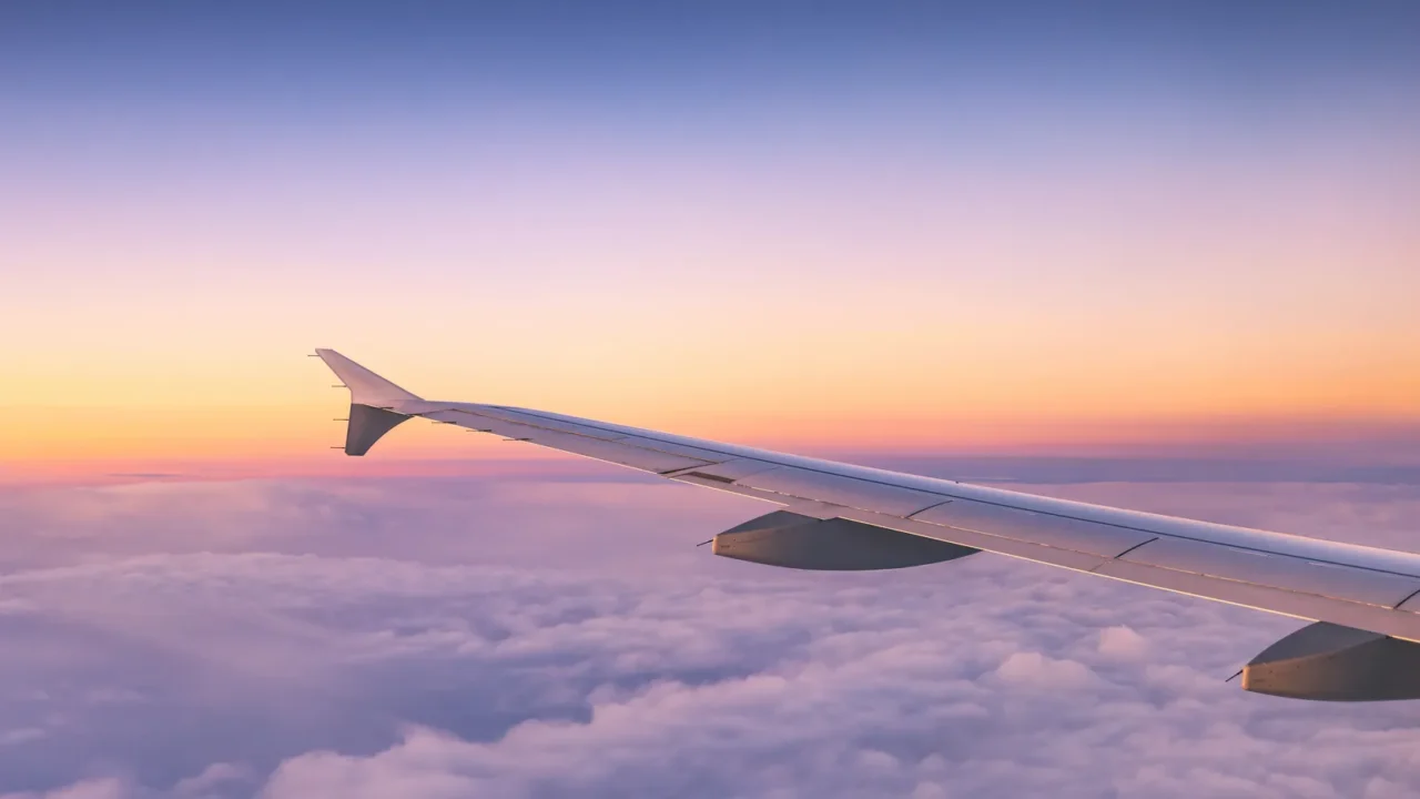 airplane flying over color sky clouds during scenic sunset or