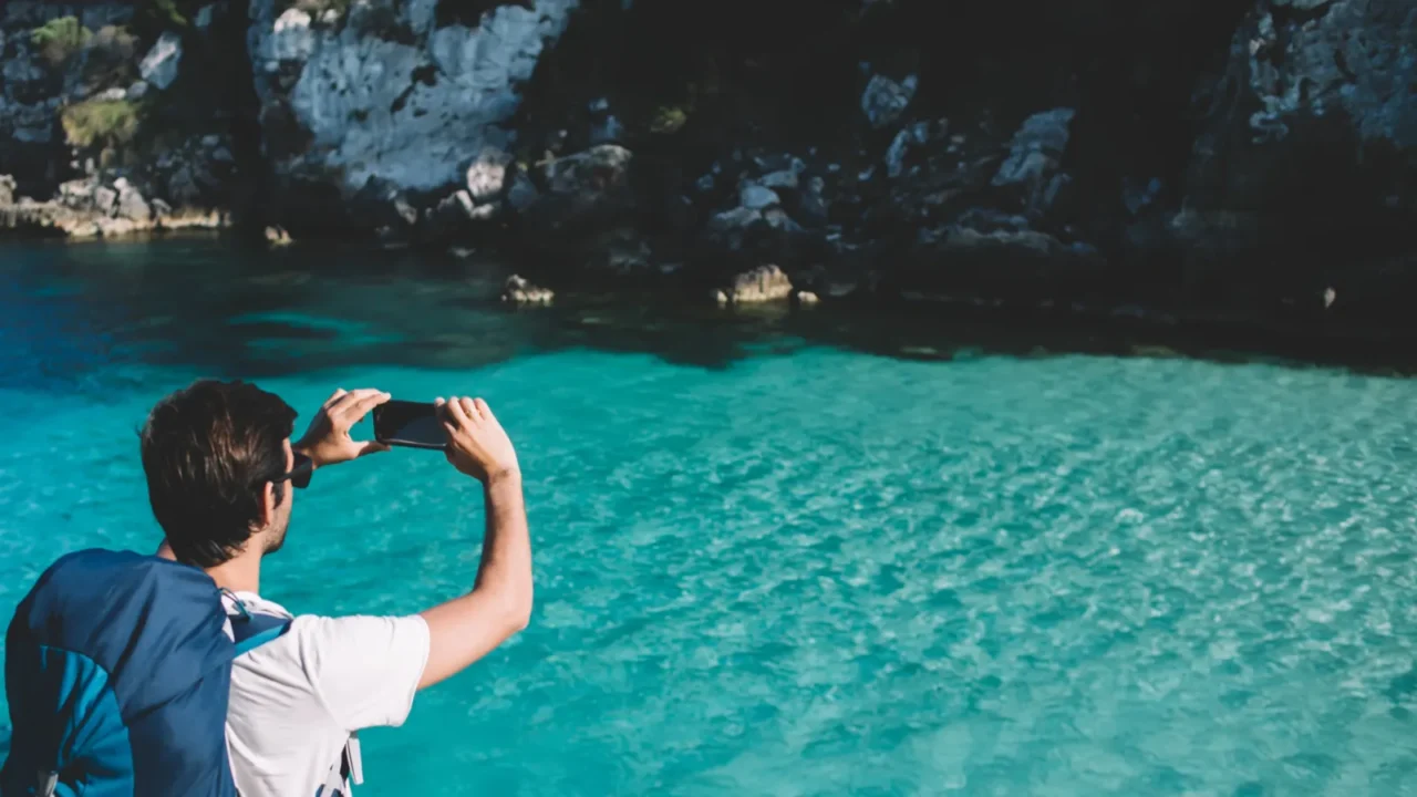 back view of male backpacker shooting video travel vlog for