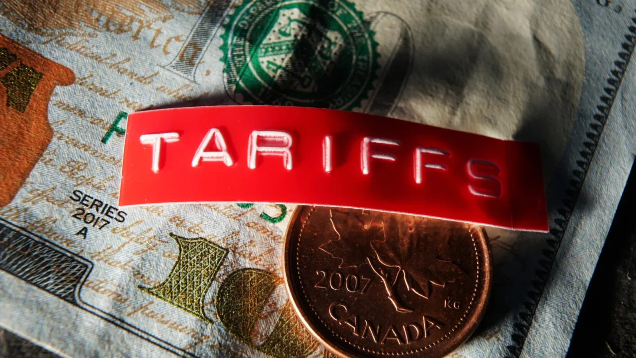canada coin and tariff label on a us hundred dollar
