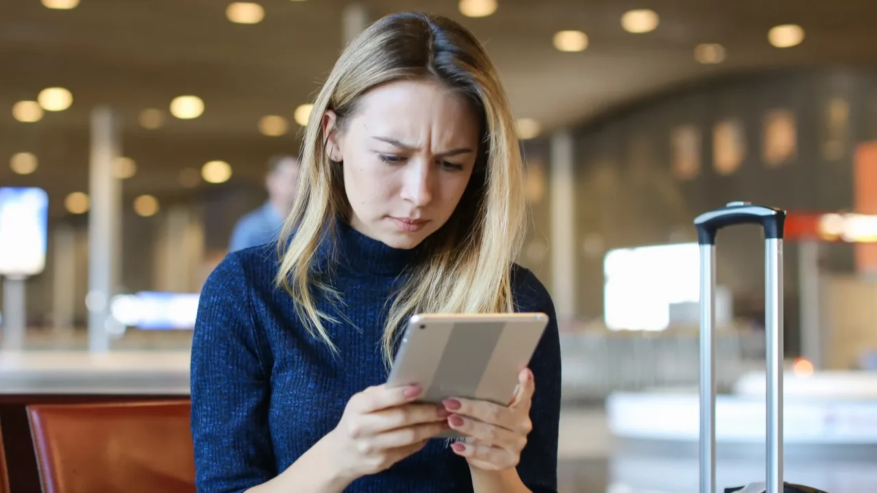 caucasian woman sitting in airport waiting room with valise and
