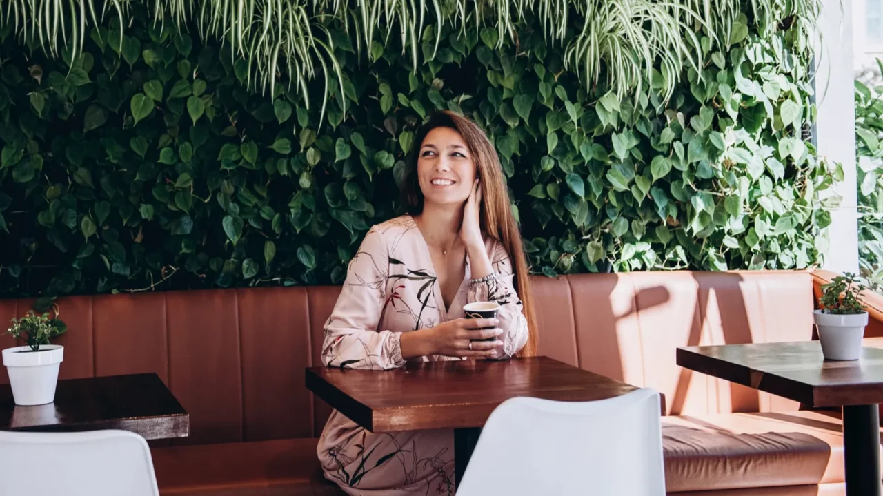 caucasian woman with long hair is sitting in cafe drinking