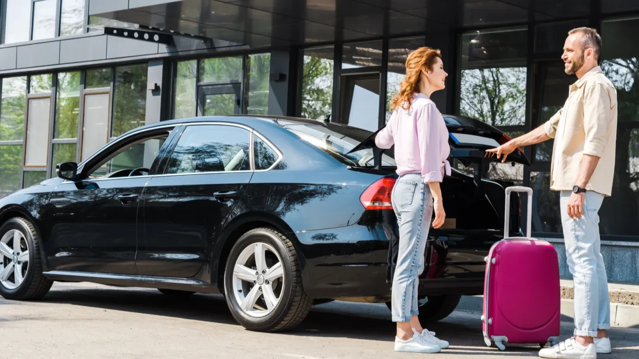 cheerful man looking at happy woman while standing near car