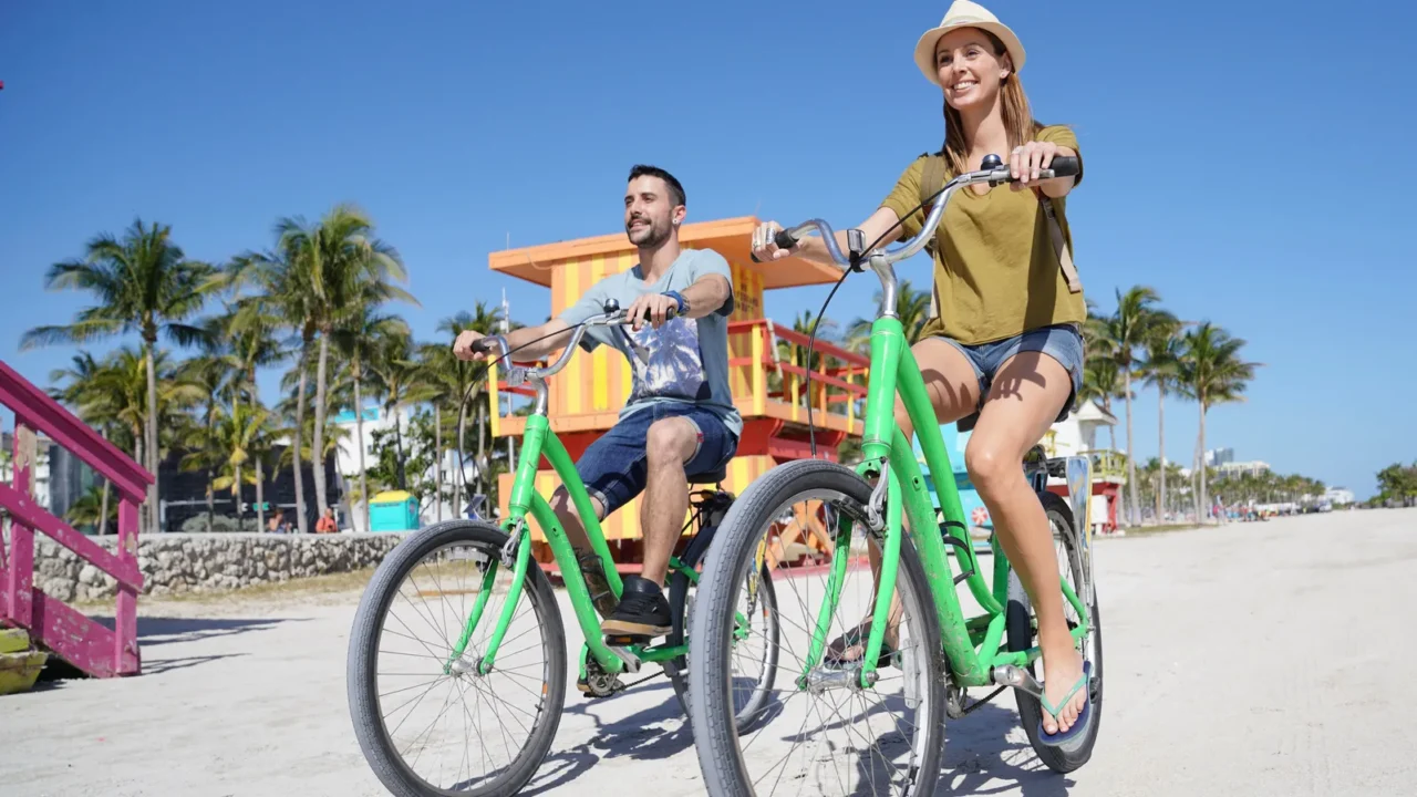 Couple of tourists riding bikes in Miami beach.