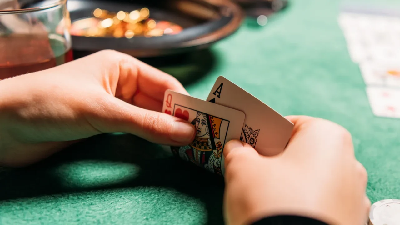 cropped image of girl holding poker cards at table in
