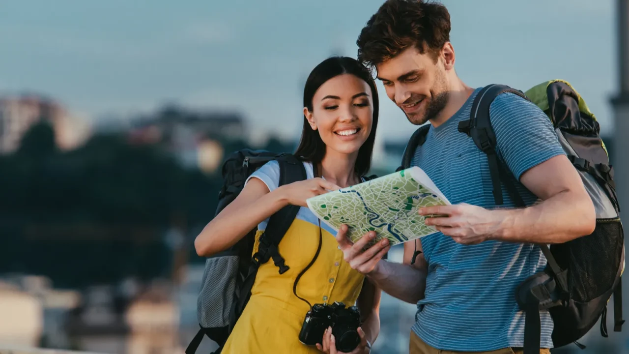 handsome man and asian woman smiling and looking at map