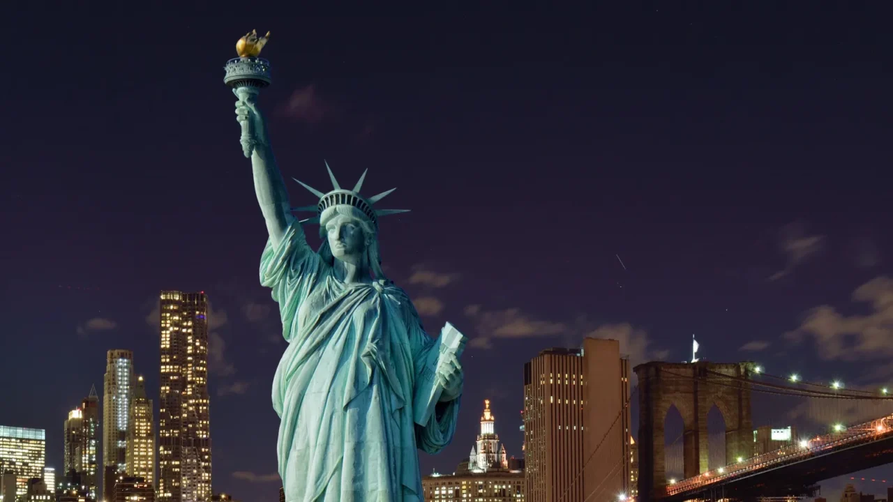 manhattah skyline with brooklyn bridge at night and statue of