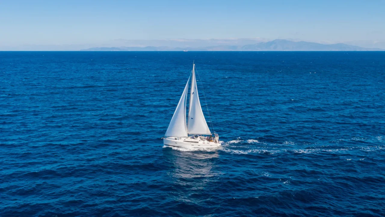 sailing sailboat with white sails blue sky and rippled sea