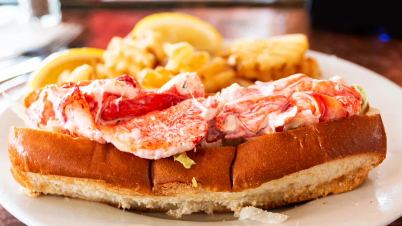 side view of a lobster roll served with waffle fries