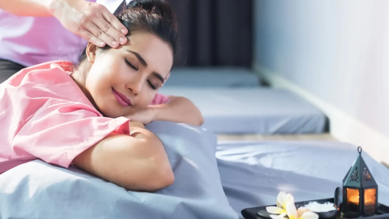 thai head massage on bed by masseuse with candle and