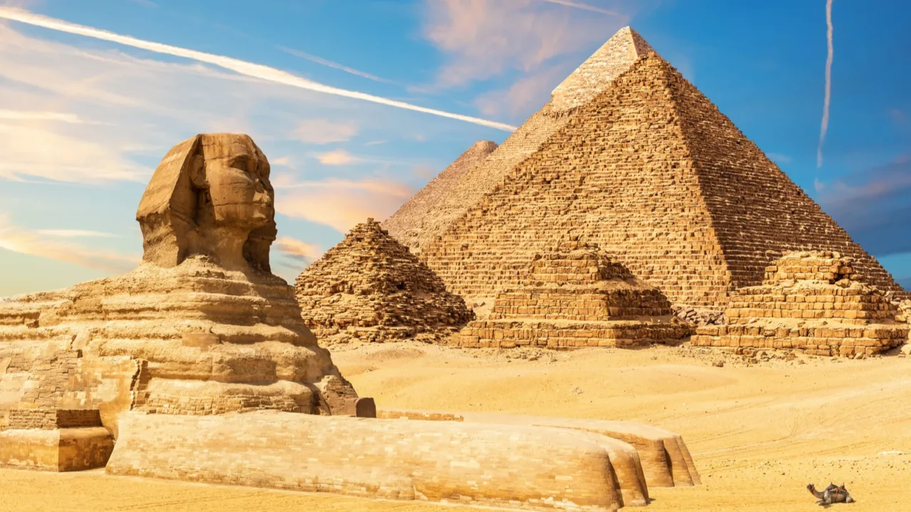 the sphinx next to the pyramids in the sands of