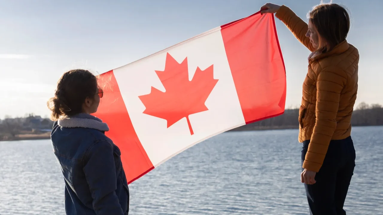 two women hold the canadian flag on a sunny day