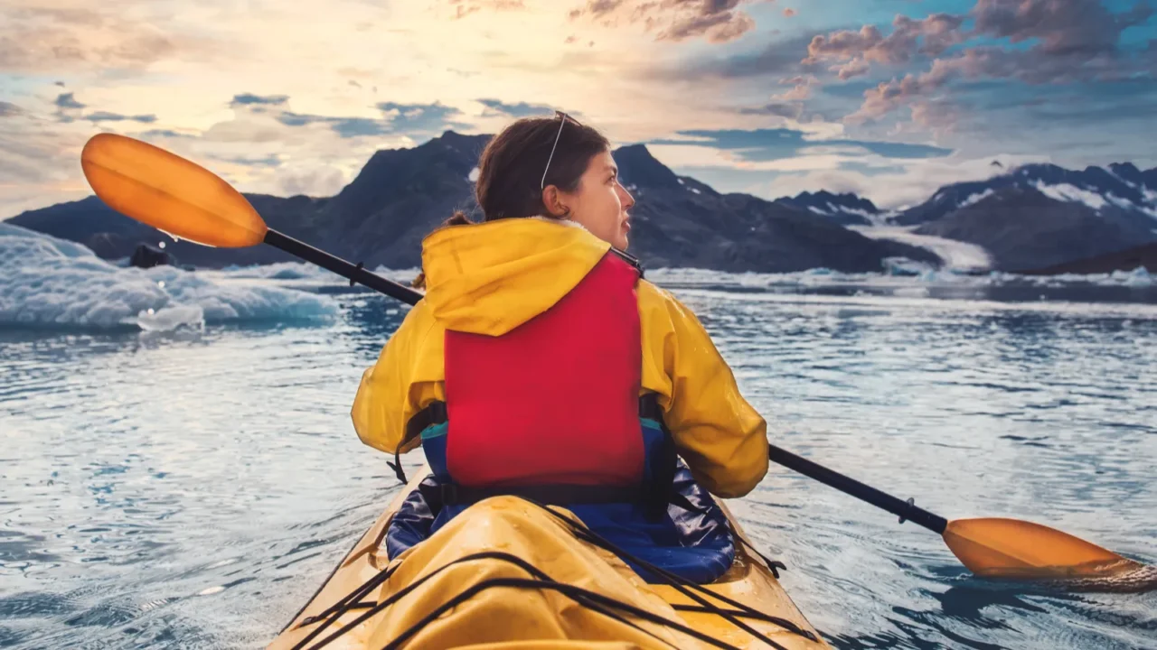 woman paddle a canoe on an icy bay in alaska