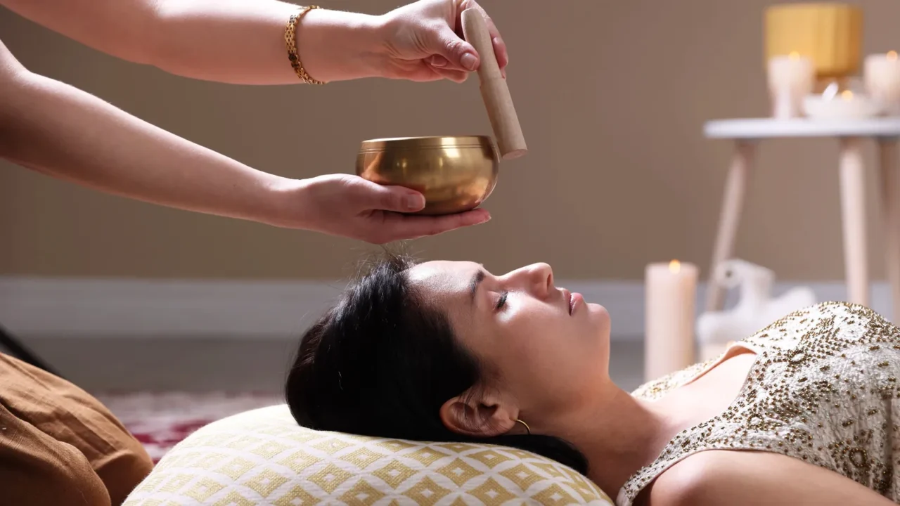 woman undergoing singing bowl therapy lying on floor indoors