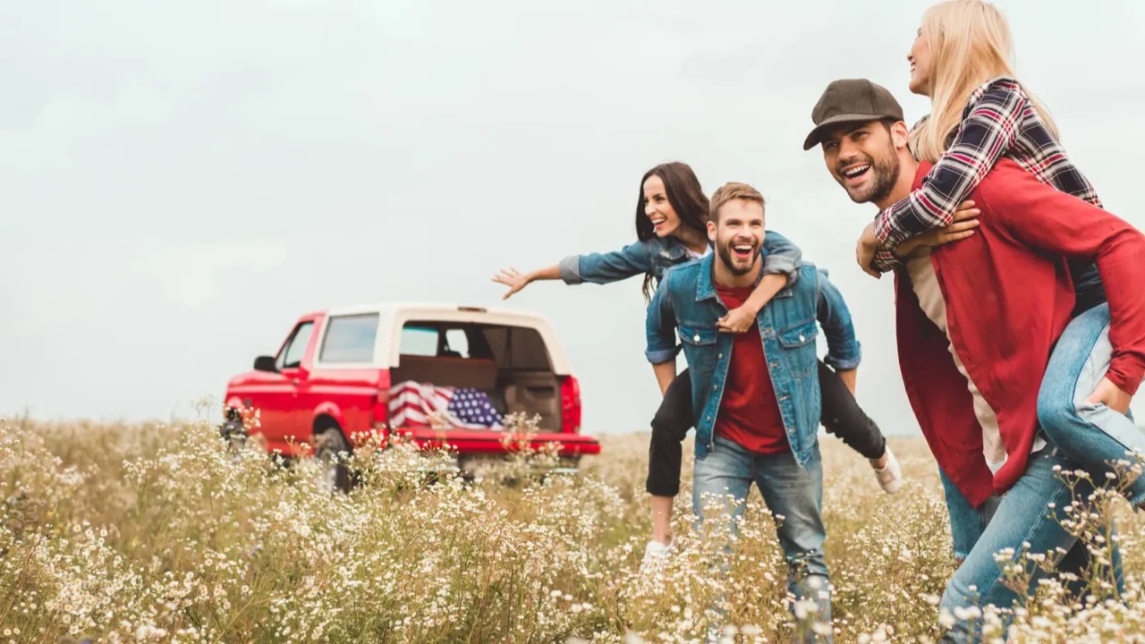 young happy women piggybacking on boyfriends in flower field