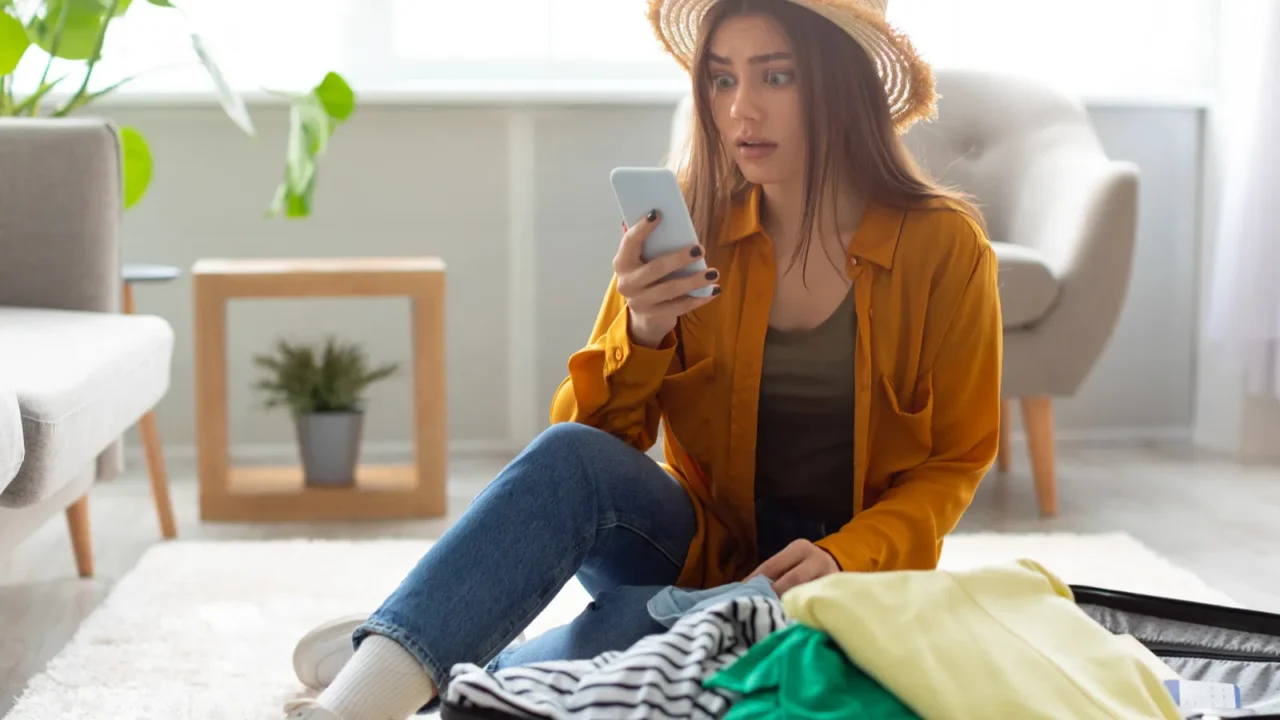 young woman staring at smartphone screen feeling shocked about cancelled