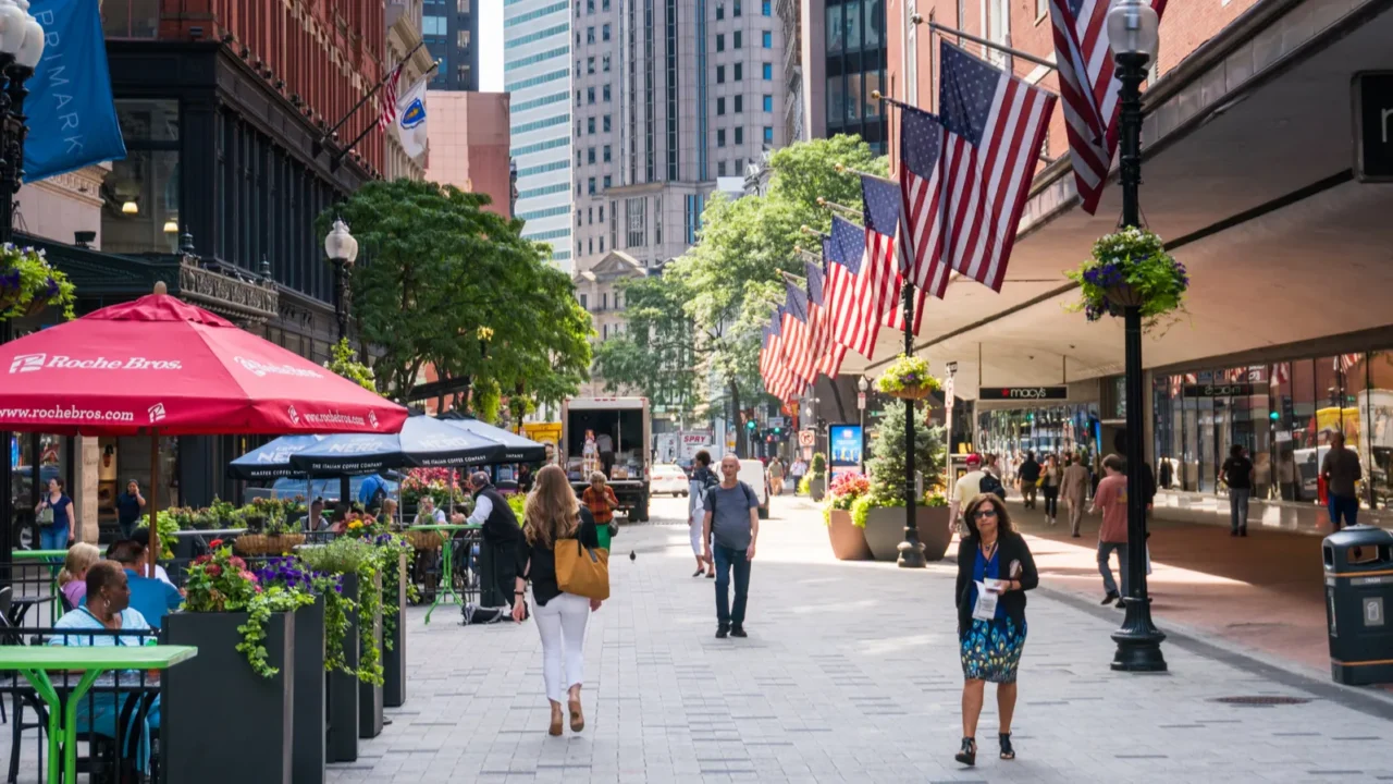 People stroll through the streets and among the skyscrapers of Boston during a sunny day.