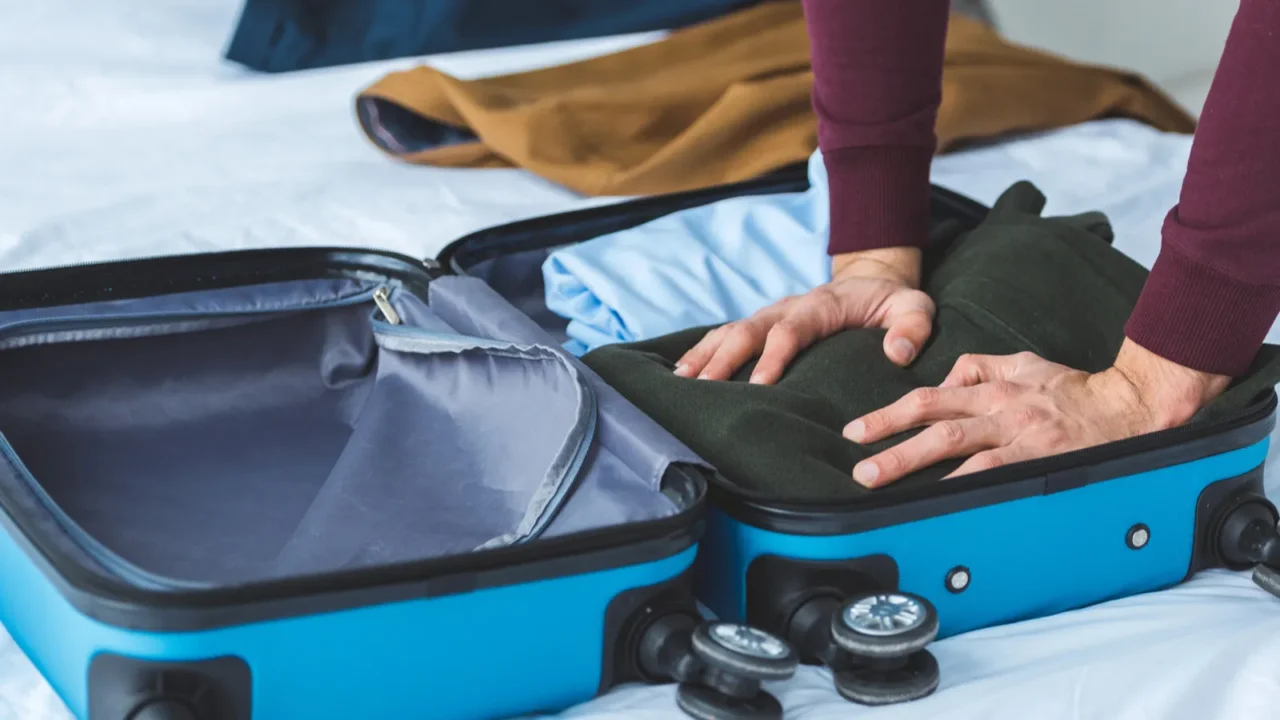 cropped view of man packinag clothes into travel bag