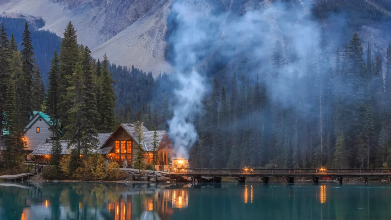 emerald lake in canada with a cozy lakeside cabin glowing