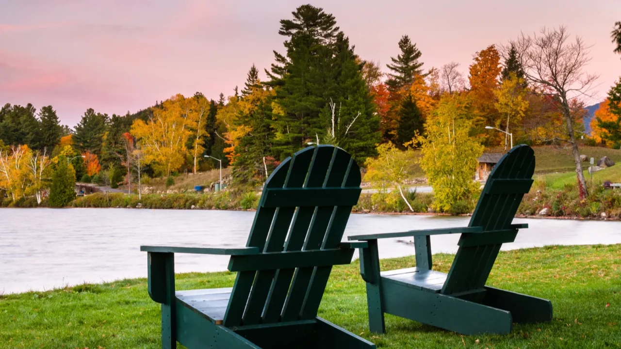 empty adirondack chairs on grass near the shore of a