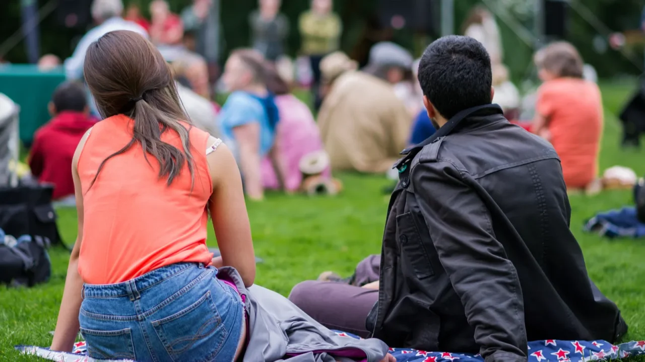 friends sitting on the grass enjoying an outdoors music cultur