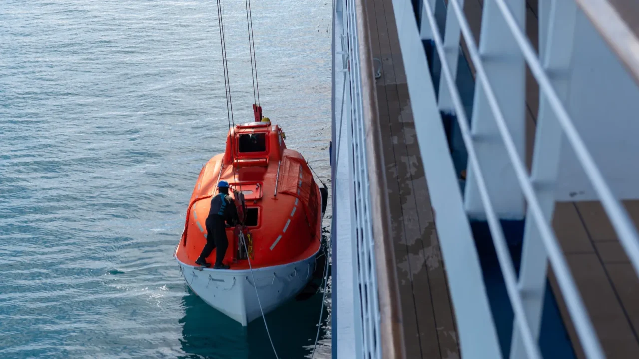 lowering orange lifeboat to water in arctic waters svalbard abandon