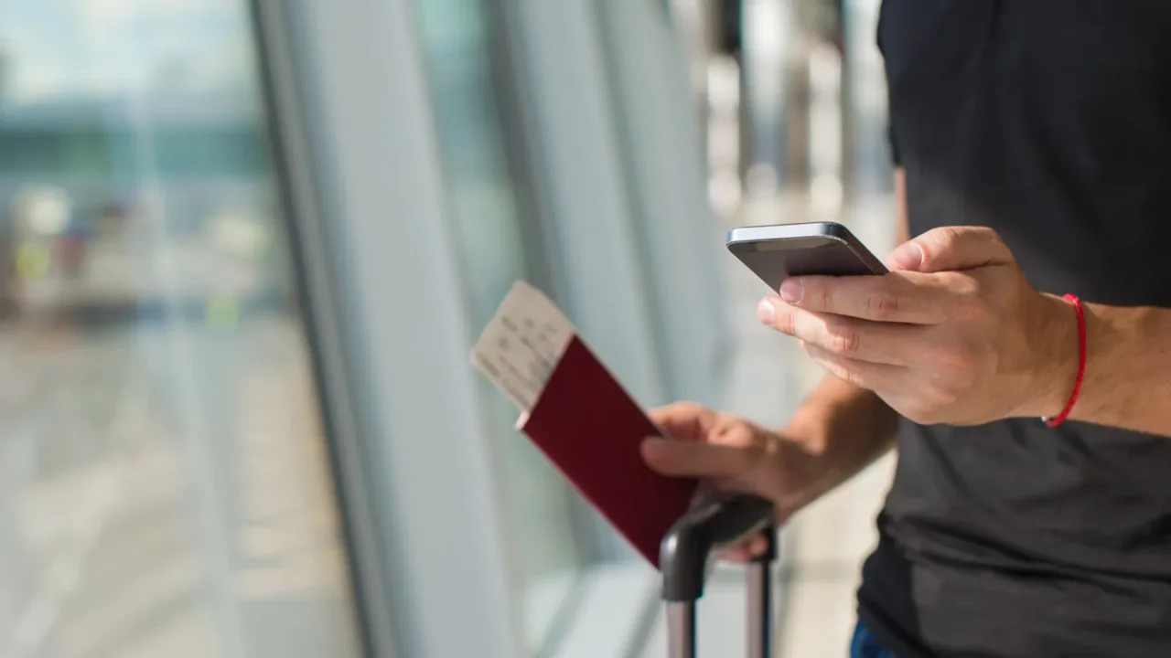 man holding cell phone passports and boarding passport at airport