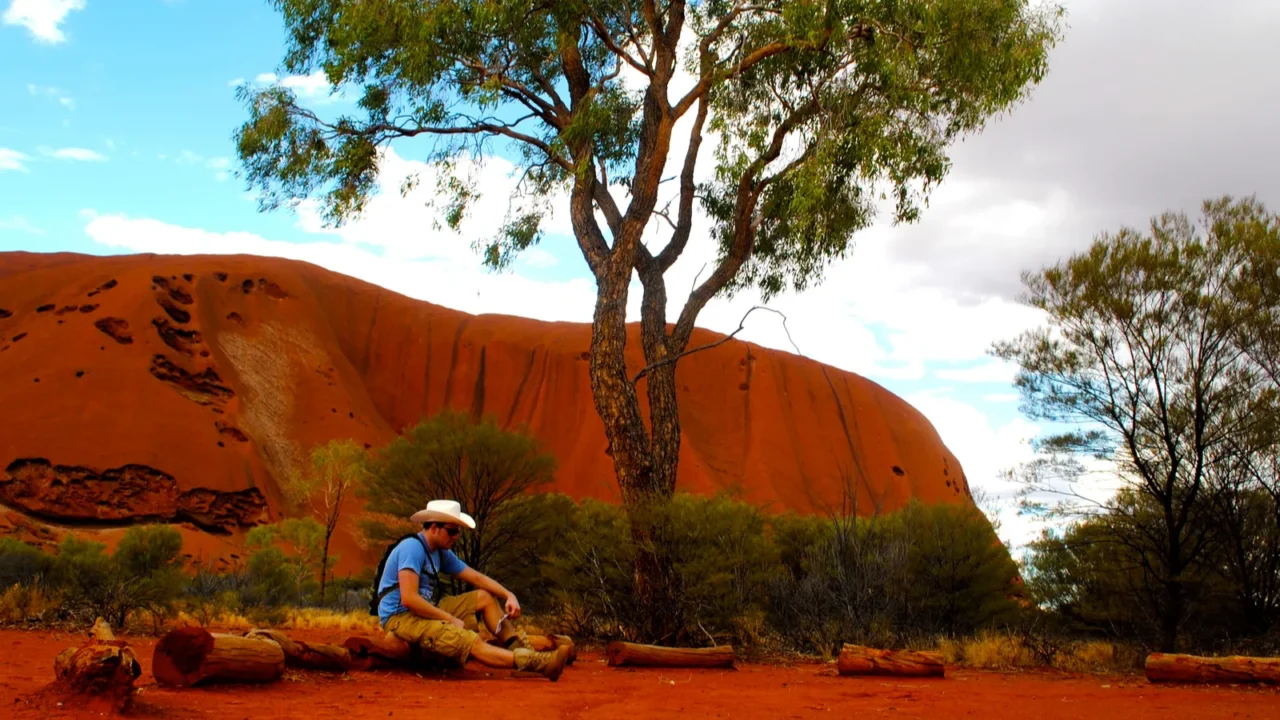 man sits before ayers rock uluru australia