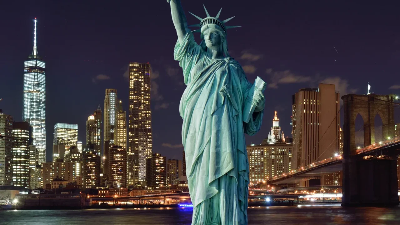 manhattah skyline with brooklyn bridge at night and statue of