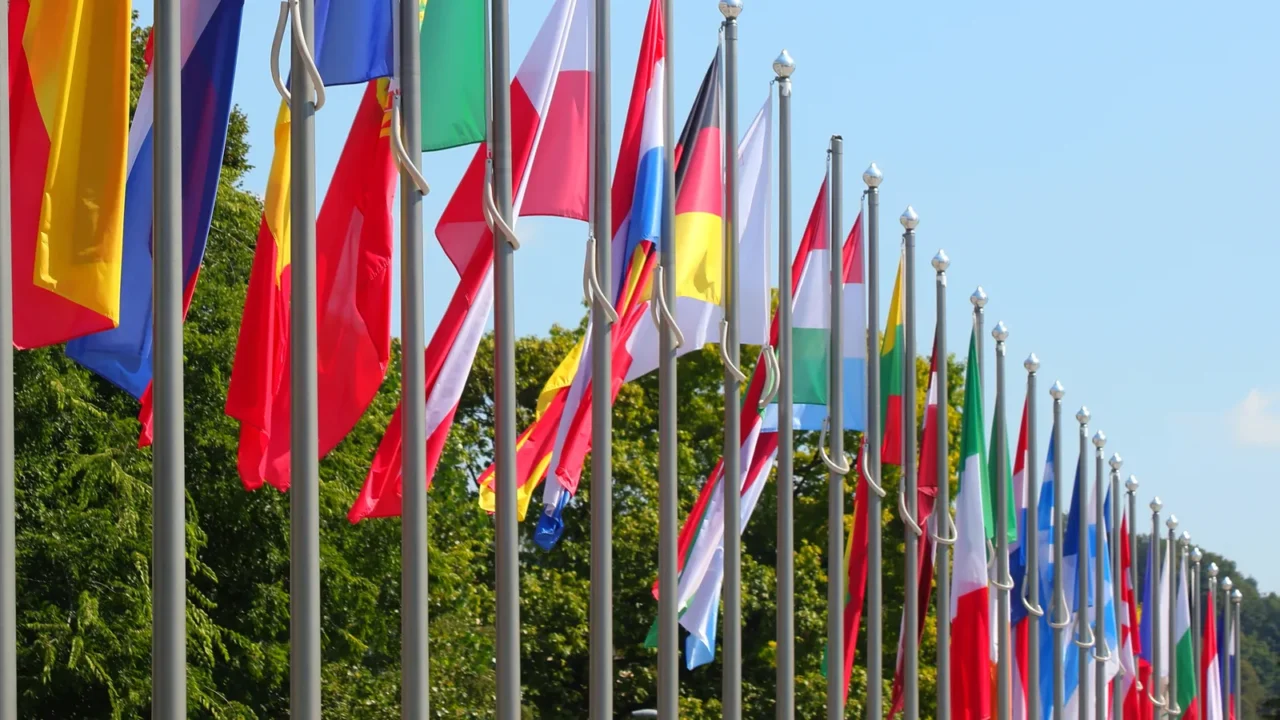 many colorful flags of world states lined up on poles