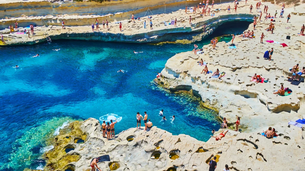Tourist on the beach of St Peter's Pool, Marsaxlokk, Malta.