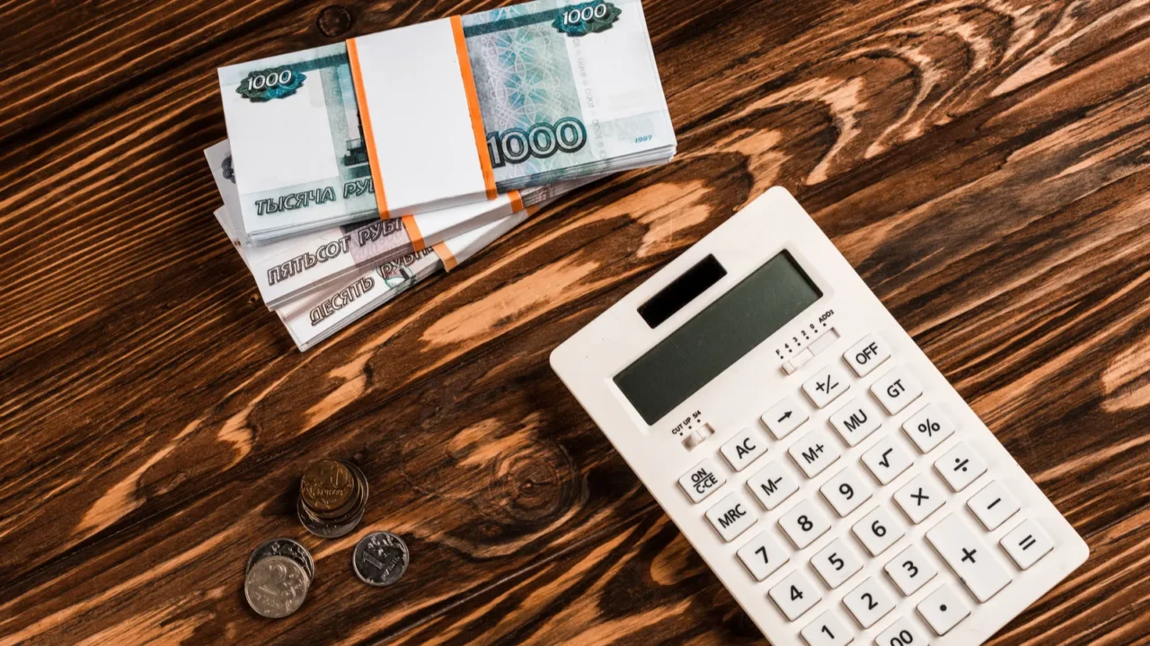overhead view of white calculator near russian money on wooden