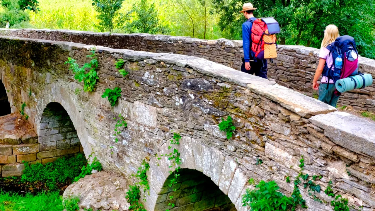 pilgrims on the ponte da aspera on the camino de