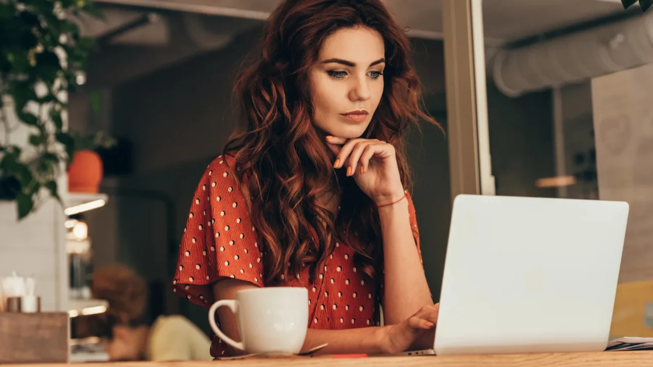 portrait of young blogger working on laptop in coffee shop