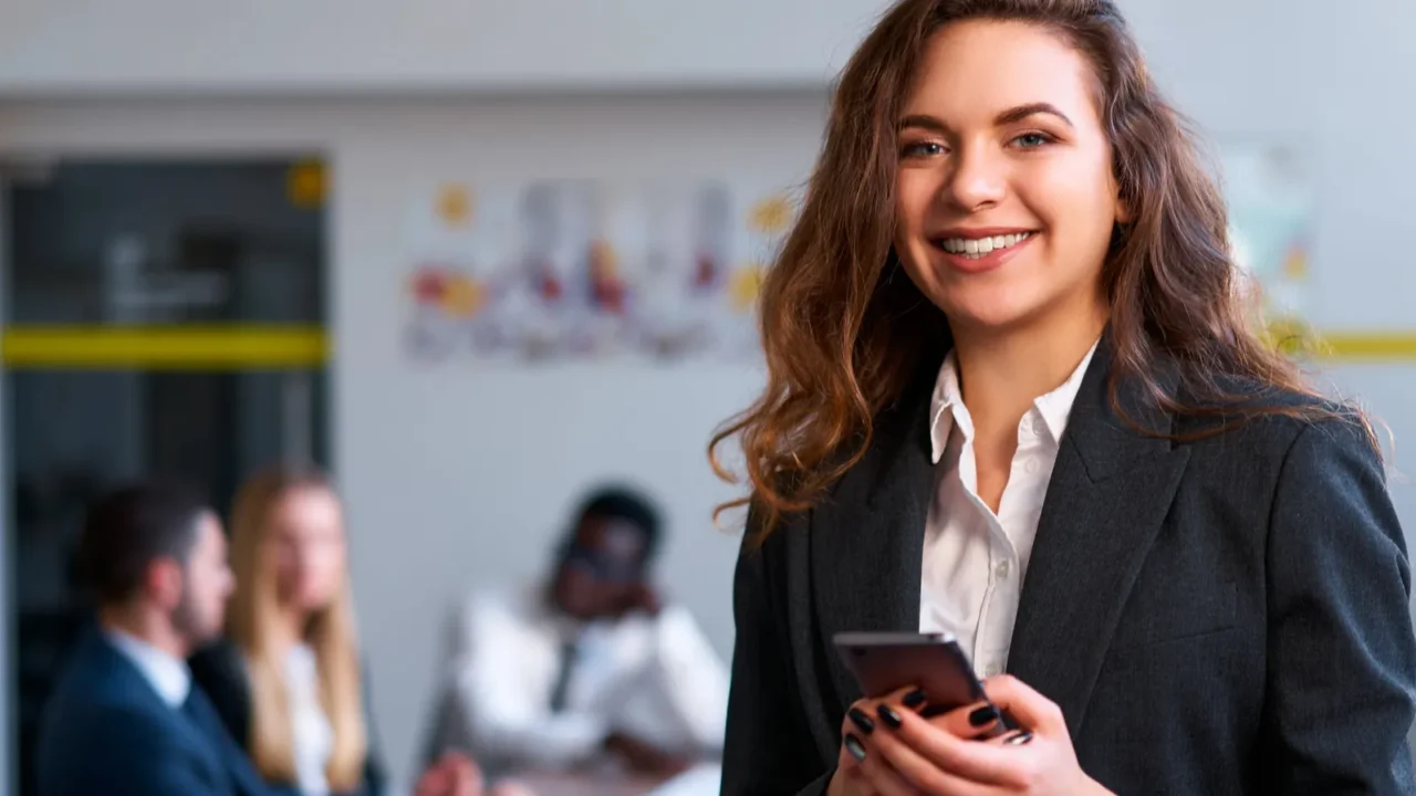 professional female checks email manages tasks smiles at camera confident