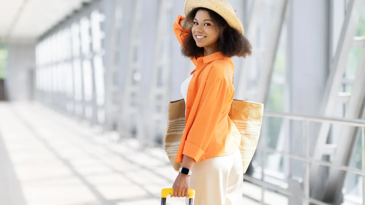 rear view of young black female traveler walking with yellow