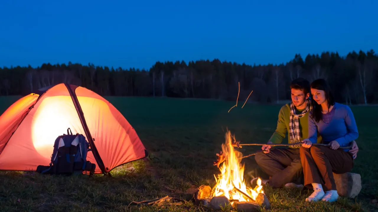 tent camping car couple sitting by bonfire