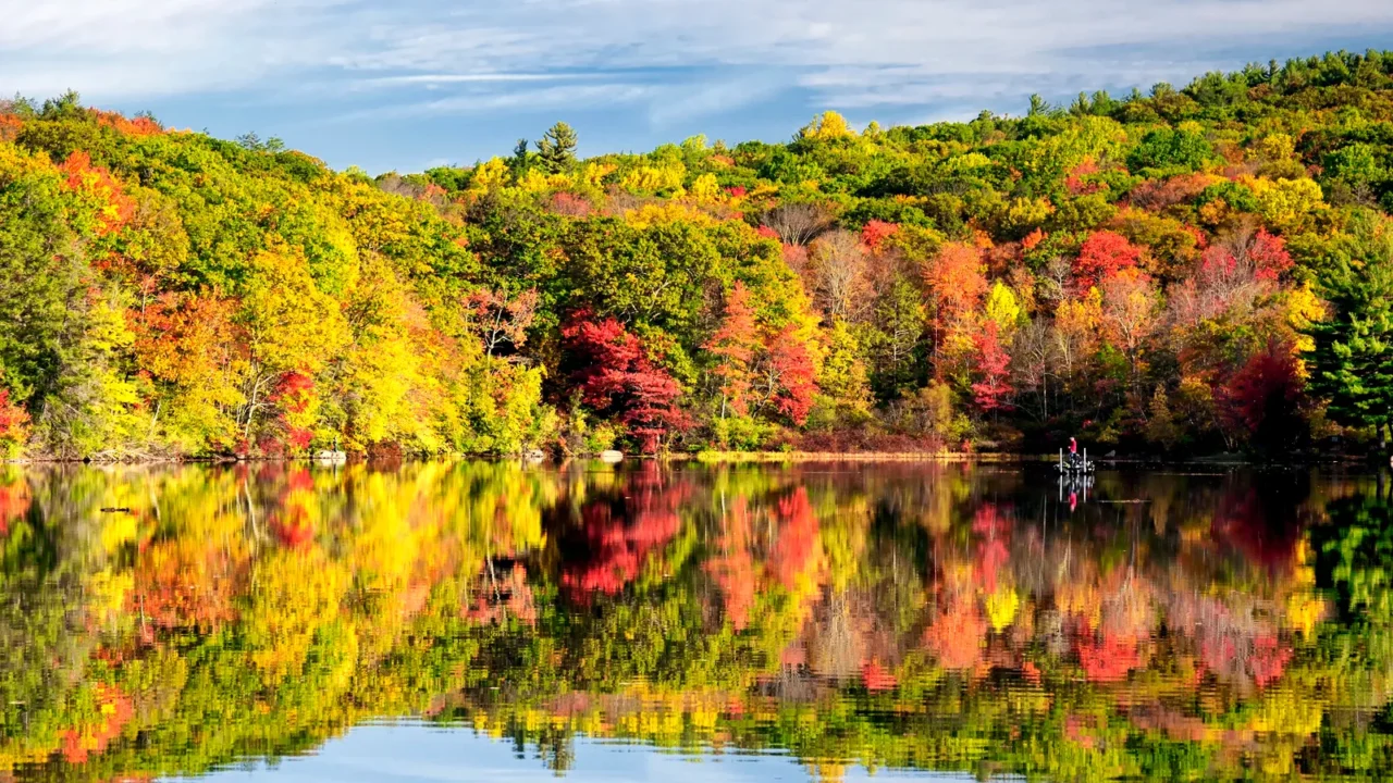 the colorful trees of autumn reflecting off of the waters