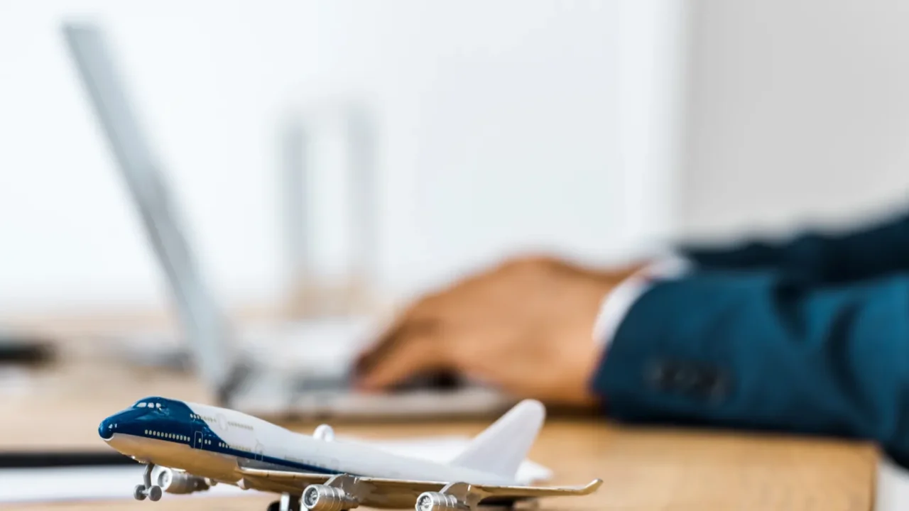toy airplane at wooden table with office worker using laptop