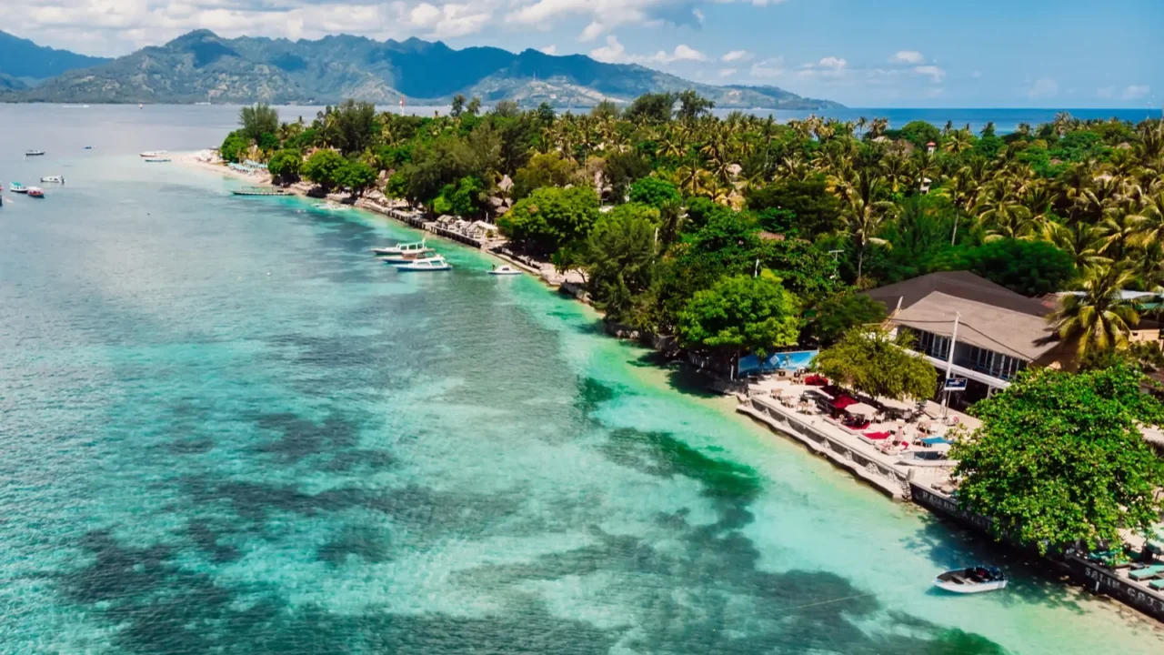 tropical island with village beach and turquoise ocean aerial view
