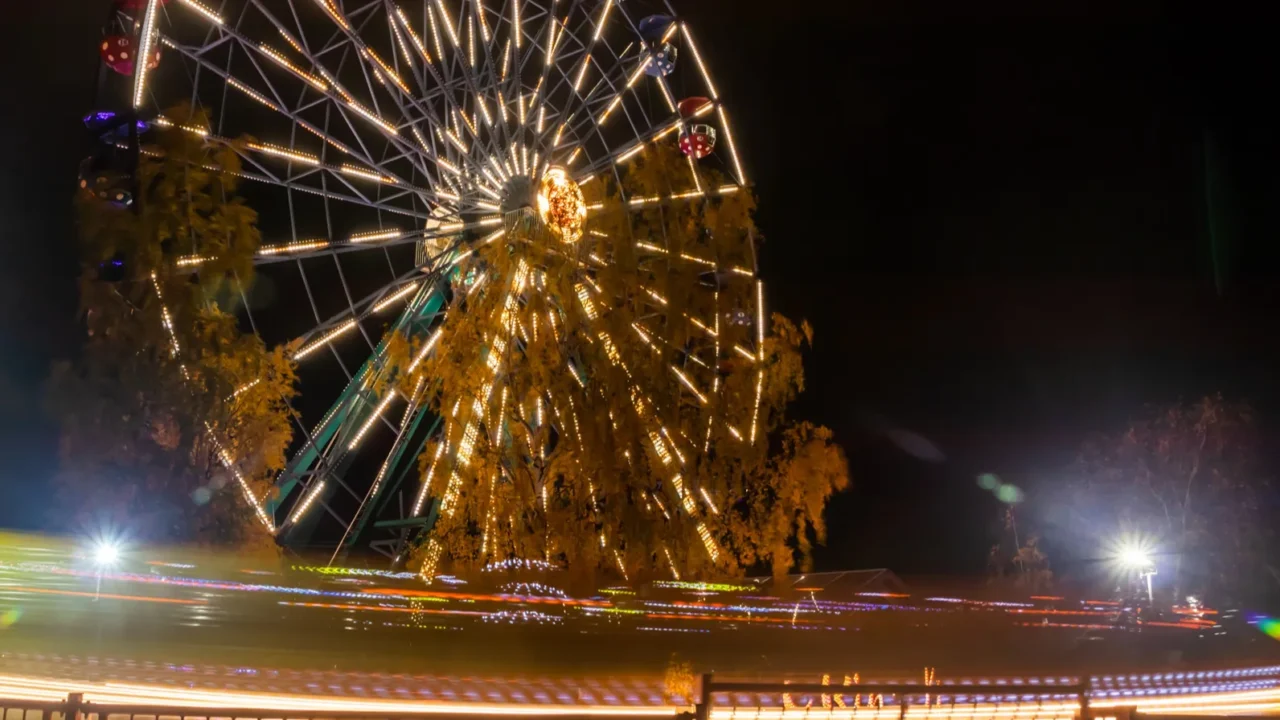two rides in motion in amusement park night illumination long