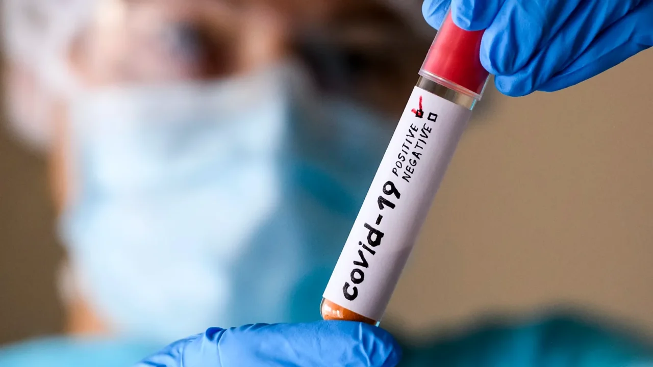 woman in protective suit hold test tube with positive result